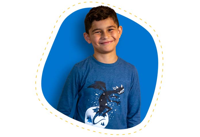 Boy with short black hair smiling while wearing a blue T-shirt with a dragon on it