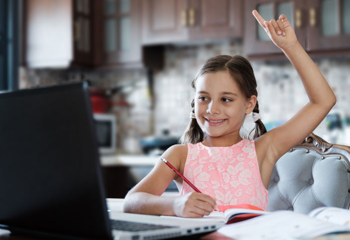 Girl smiling and pointing up while writing in a book and using a laptop
