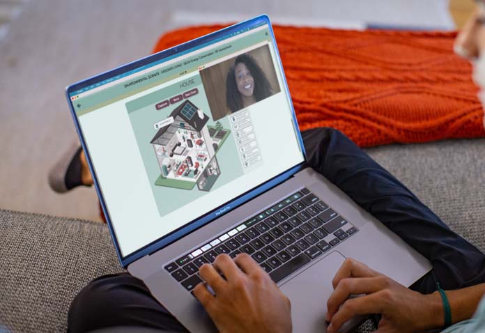 Boy sitting cross-legged on the floor while using a laptop in his lap