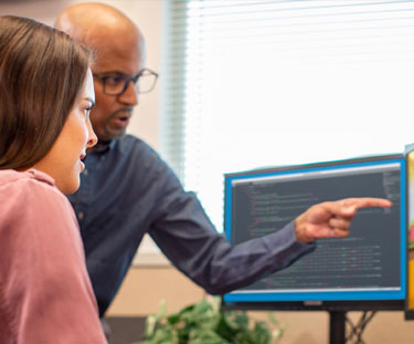 A teacher helps a student using a computer